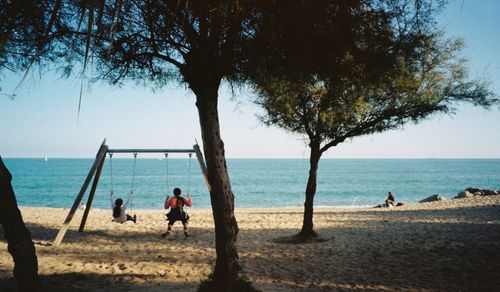 Children on swings by the sea