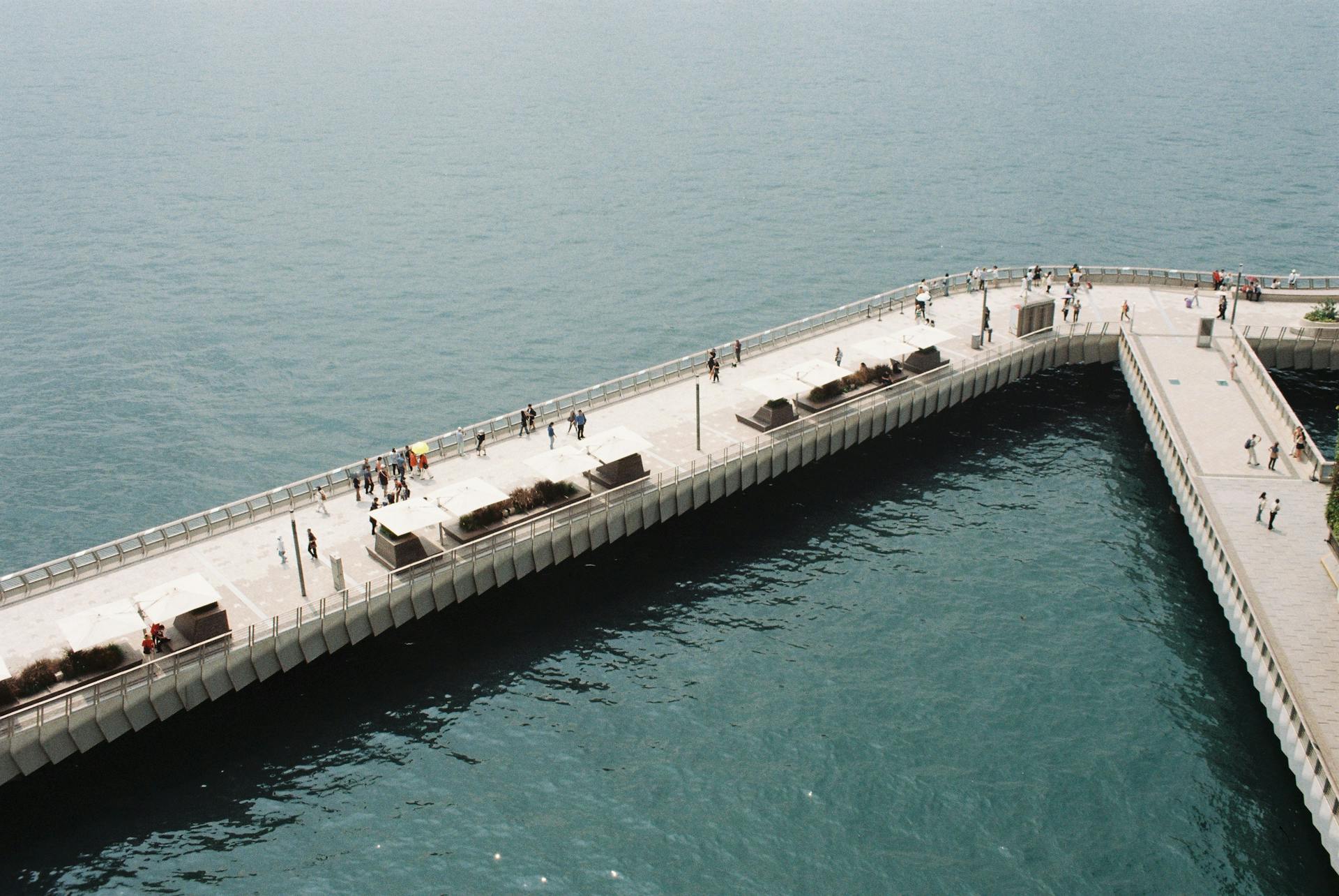 Bird's-eye view of a bustling promenade along Victoria Harbour in Hong Kong with people walking and relaxing.