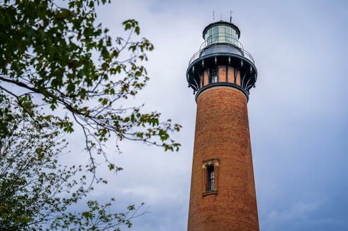 A tall brick lighthouse with a green roof