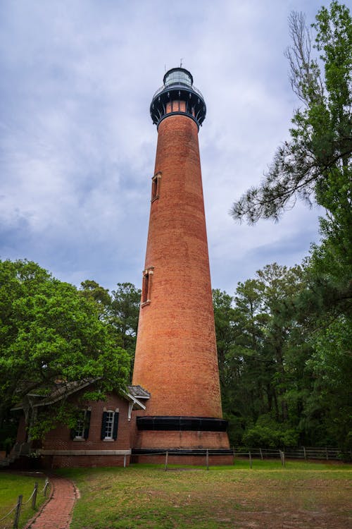 A tall brick lighthouse with a red roof