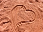 在柔软的沙子上画出的心形，在阳光下熠熠生辉，象征着爱情与浪漫