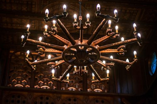 Free Elegant wooden chandelier with illuminated bulbs, showcasing intricate designs in a vintage setting. Stock Photo