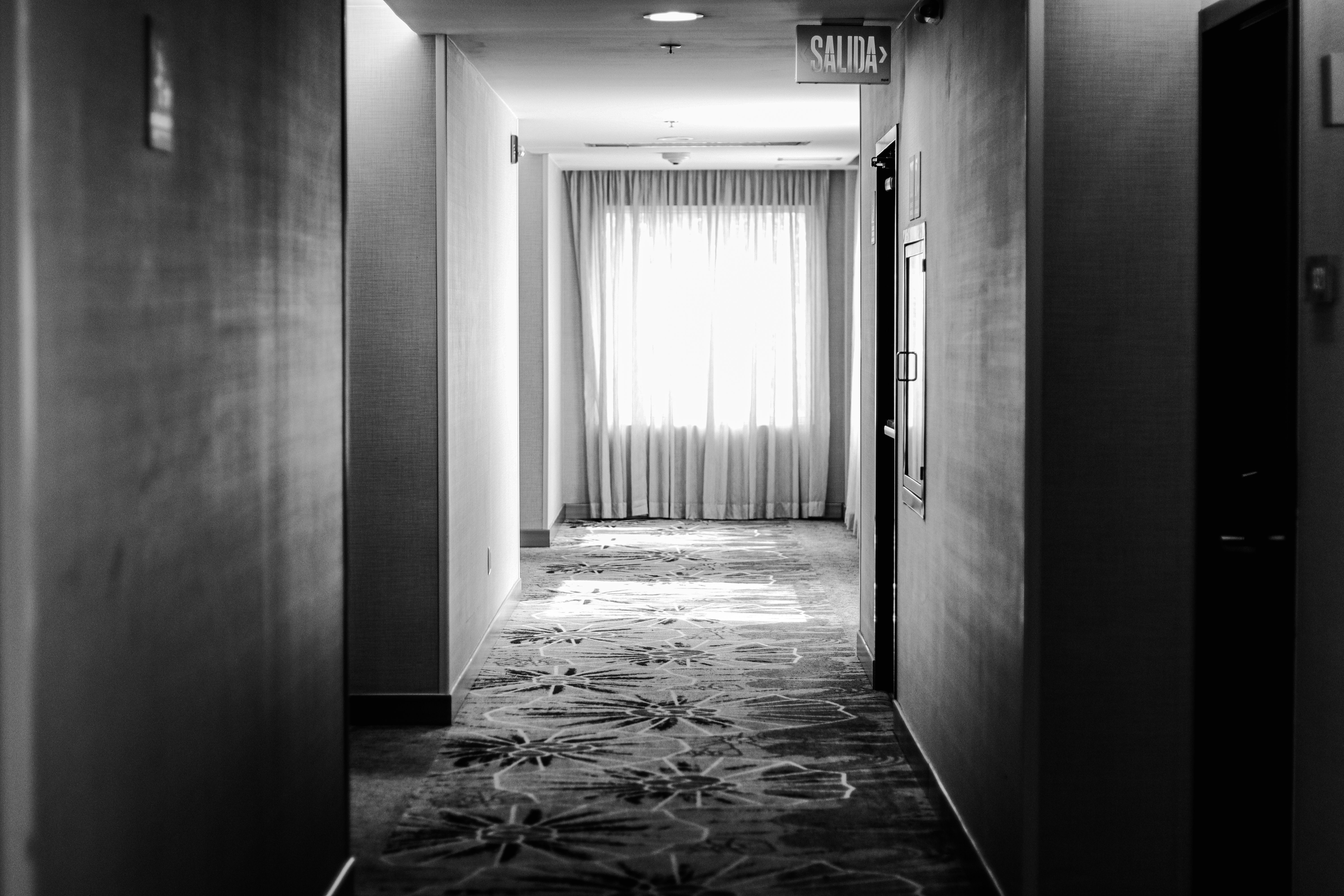 Elegant black and white hotel corridor with sunlight through curtains in Puebla, Mexico.