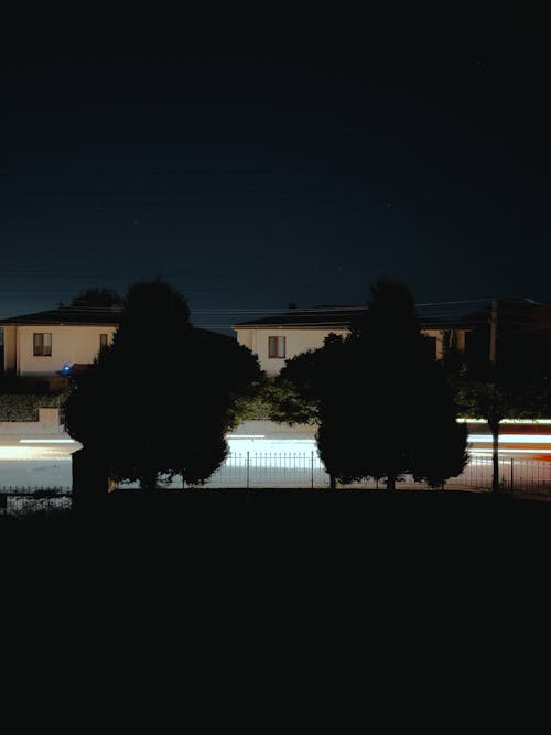 A night time photo of a street with trees and houses