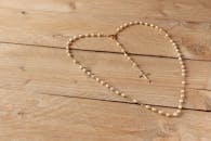 White Rosary on Beige Wooden Surface
