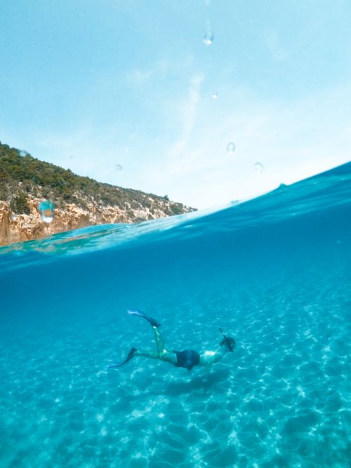 Free Man snorkeling in the clear blue waters of Sardinia, Italy, enjoying underwater adventure. Stock Photo