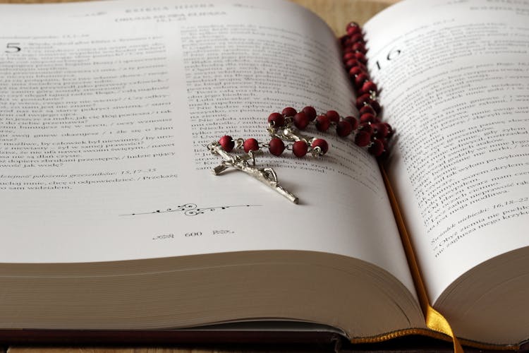 Rosary On Top Of Opened Bible Book