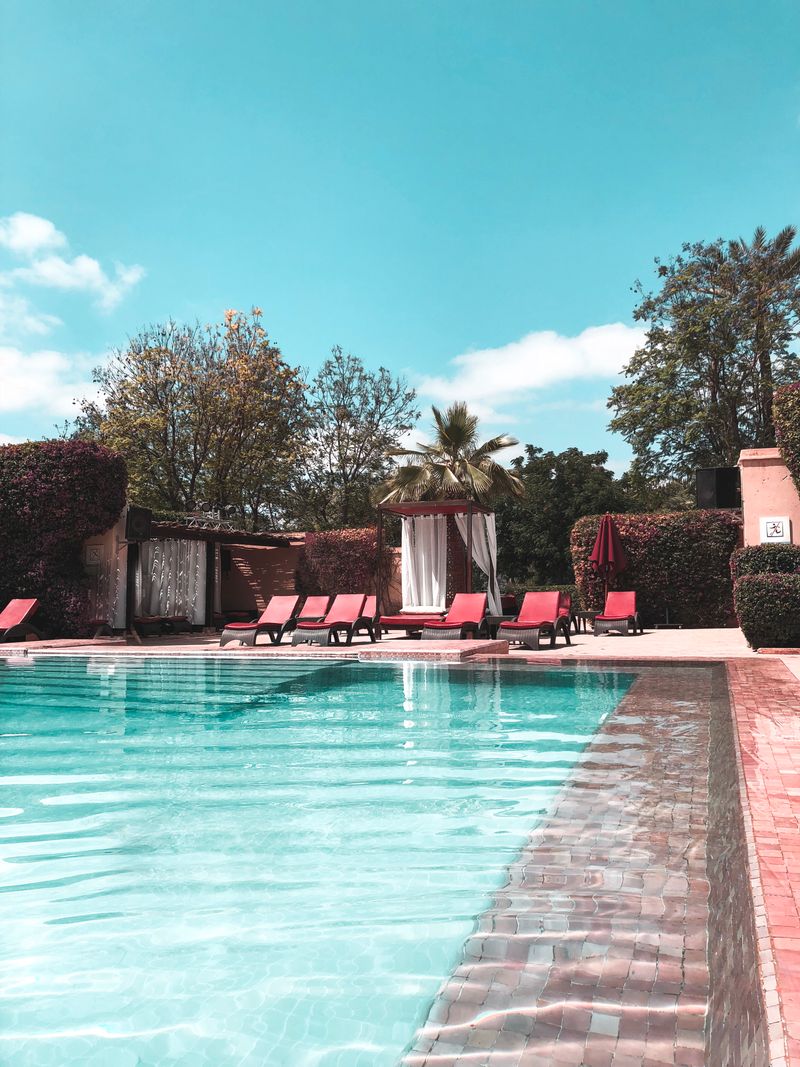 Resort-style community swimming pool with red lounge chairs