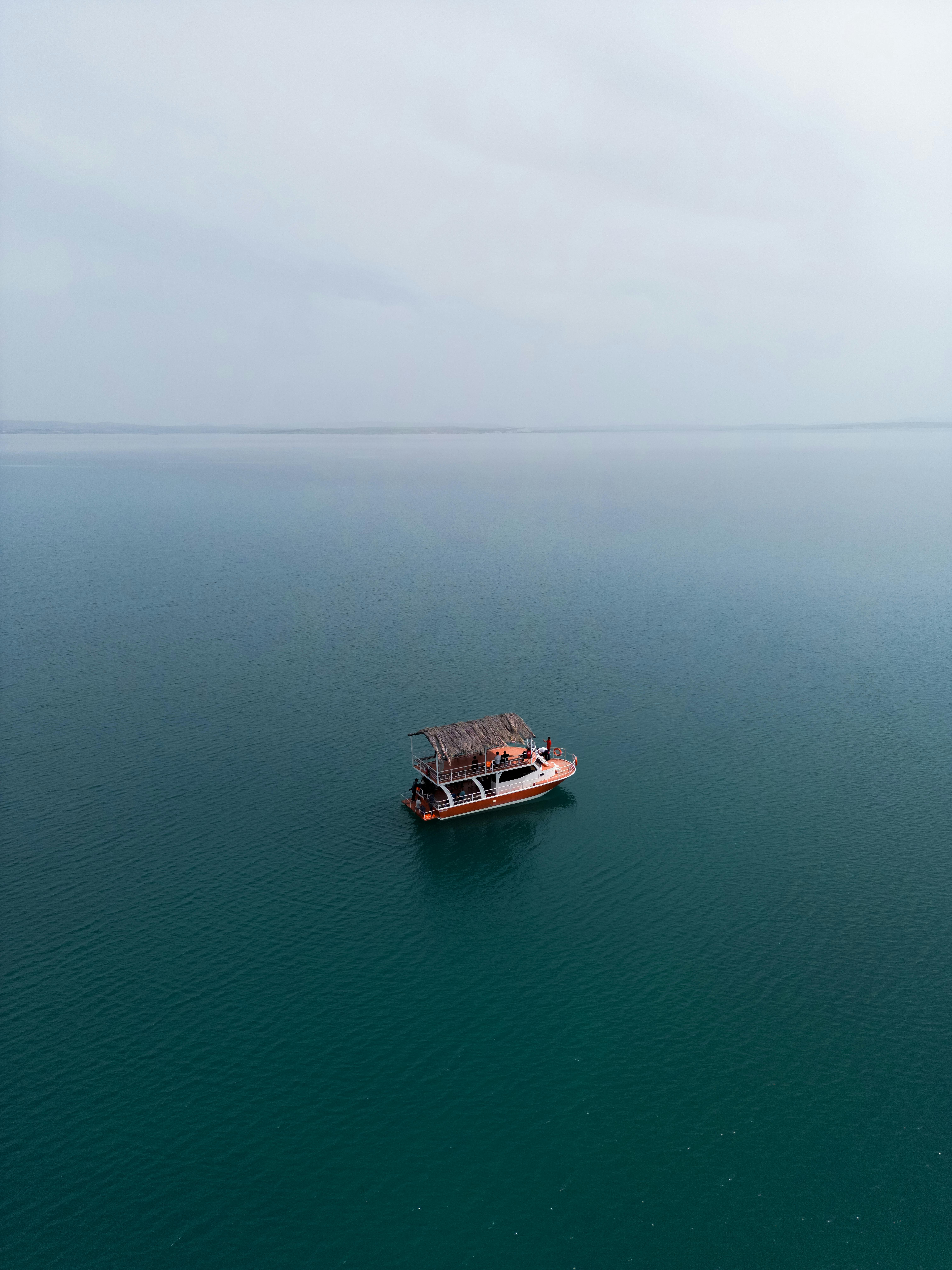 A solitary boat sails calmly across a vast, foggy lake, showcasing serene travel and nature vibes.
