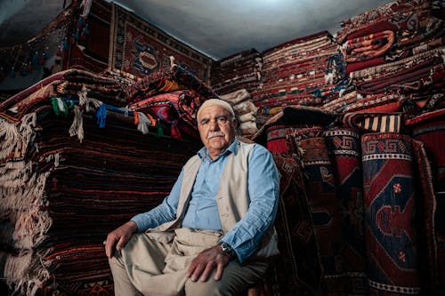 Man Sitting with Carpets behind