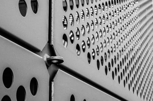 Black and white photo of a metal wall with holes