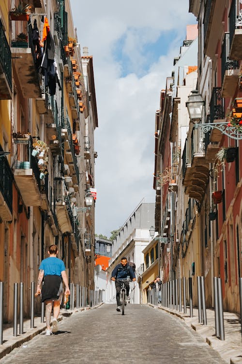 Two people walking down a narrow street in a city