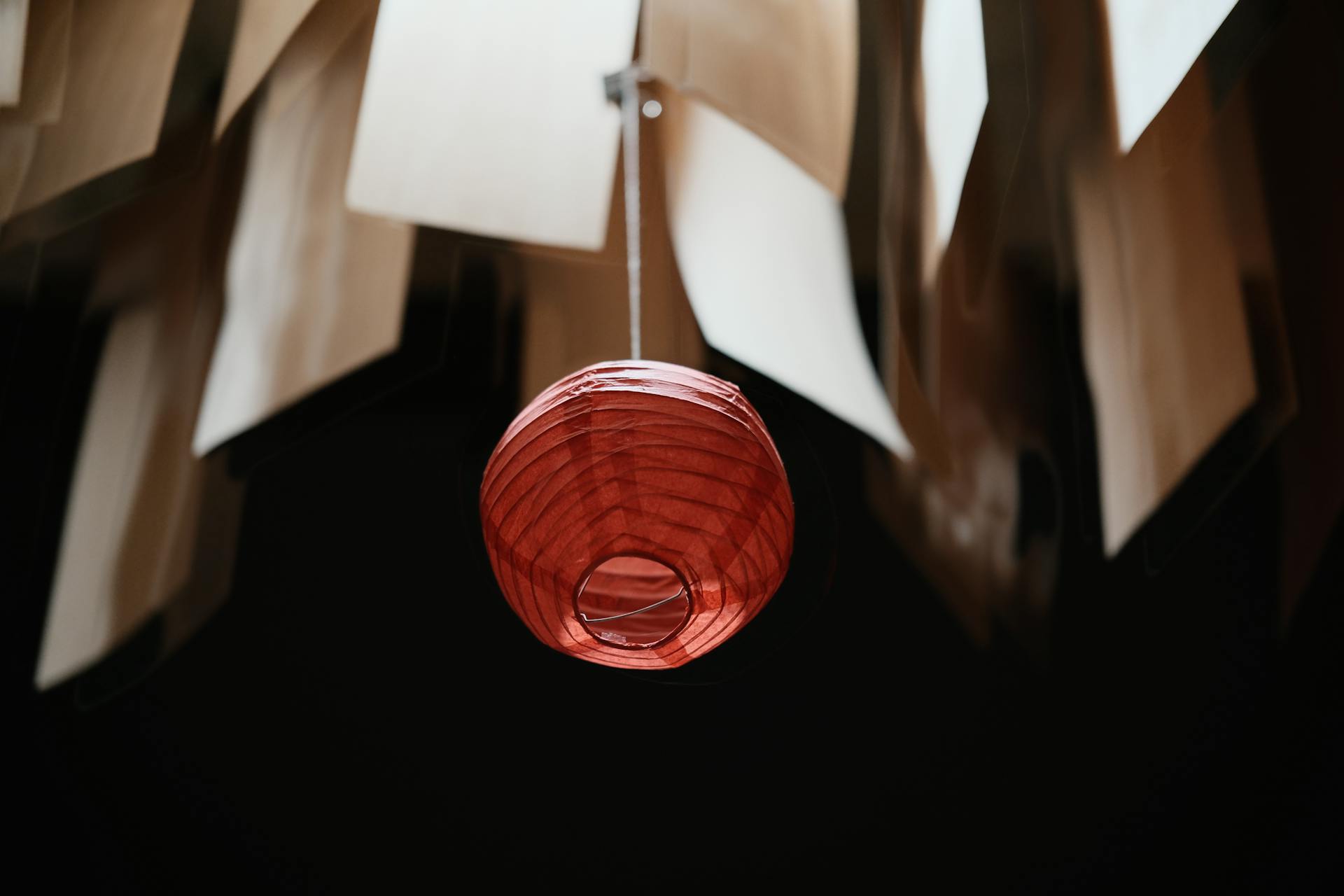 A striking red lantern hanging beneath sheets of paper for a unique decorative effect.
