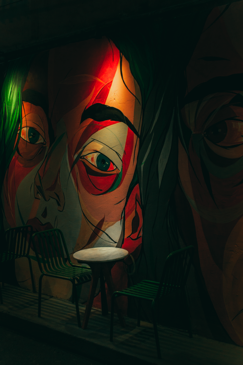 Free Moody cafe interior featuring vibrant murals and cozy seating at night. Stock Photo