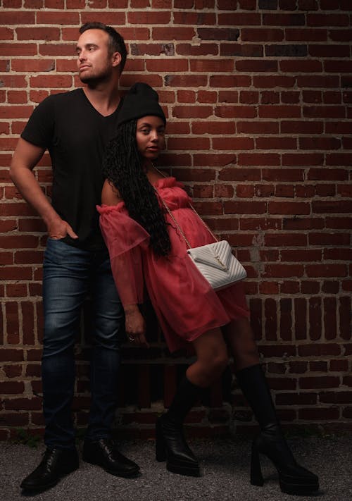 A man and woman standing next to a brick wall