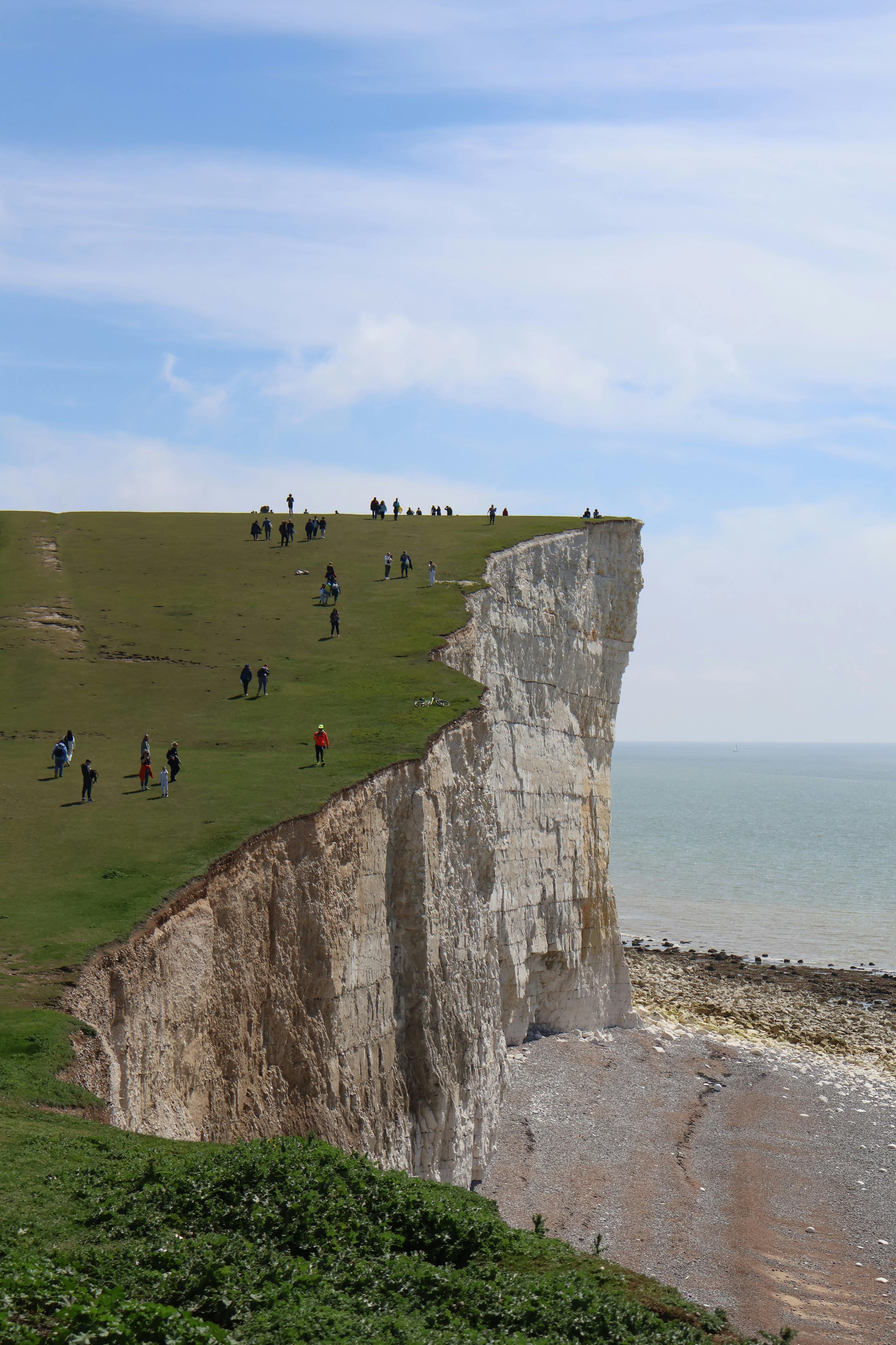 People walking on the stunning cliffs of Exceat, England, with expansive ocean views.