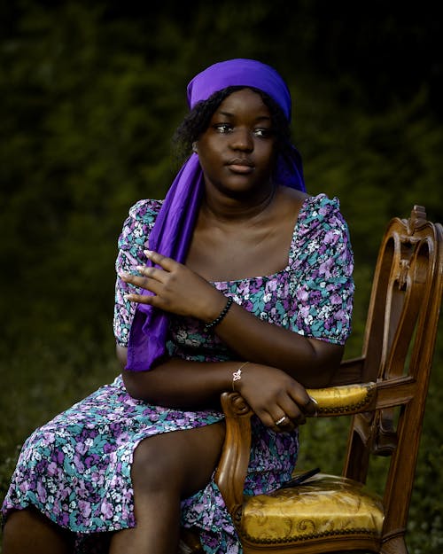 A woman in a purple head scarf sitting on a chair