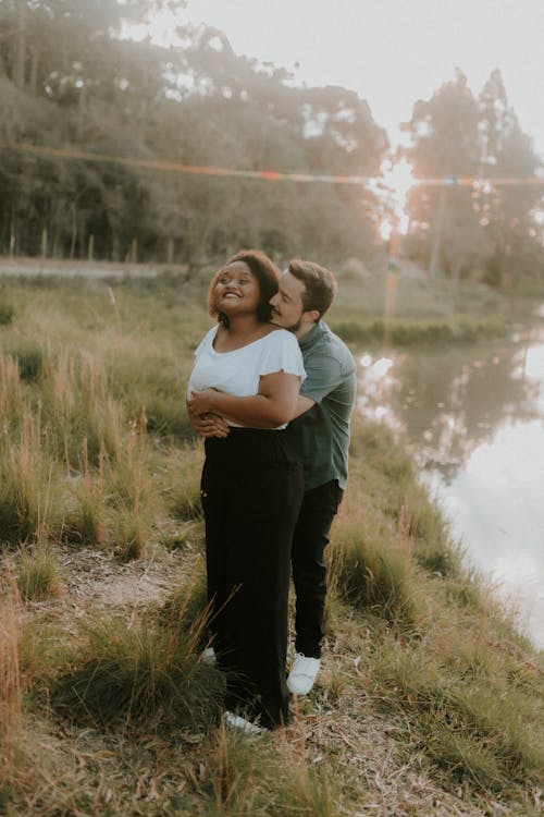 A couple embracing in front of a river at sunset