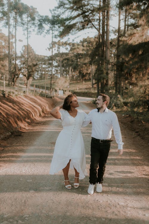 A couple walking down a dirt road in the woods