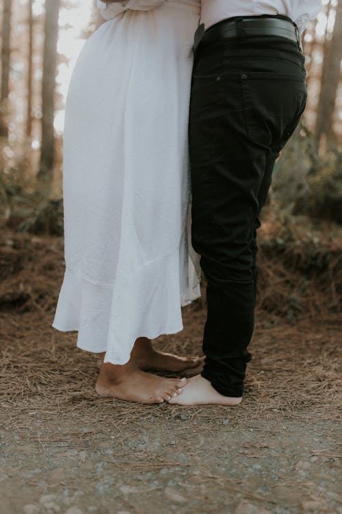 A couple standing in the woods with their feet touching