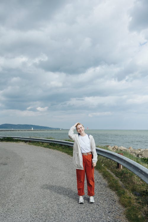 A woman standing on a road near the ocean