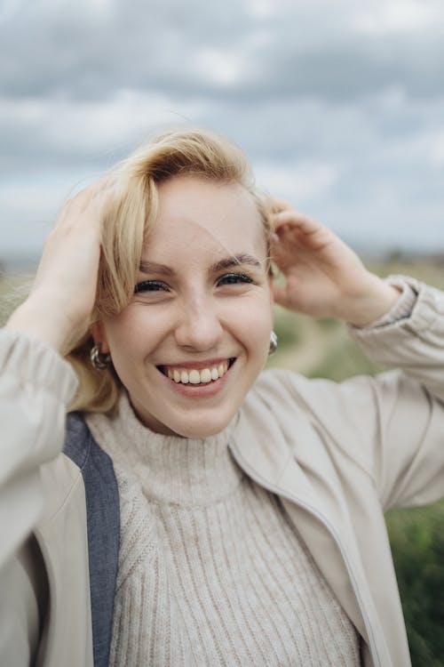A woman smiling and holding her hair up