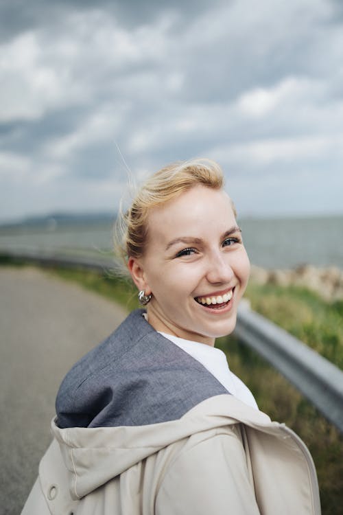 A woman smiling on a road near the ocean