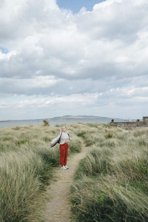 A woman walking on a path through grass and sand