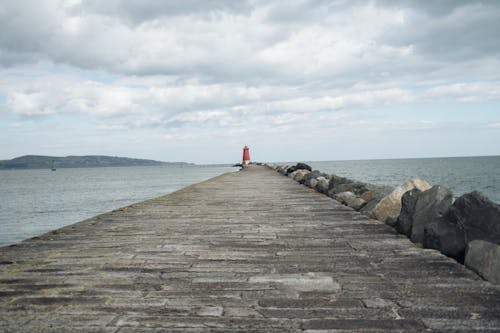 A person standing on a pier looking out to the ocean