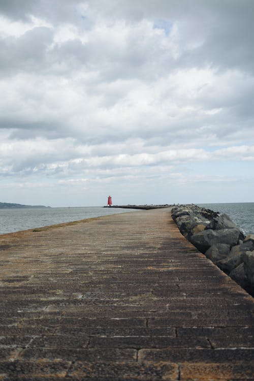 A long pier with a lighthouse in the distance
