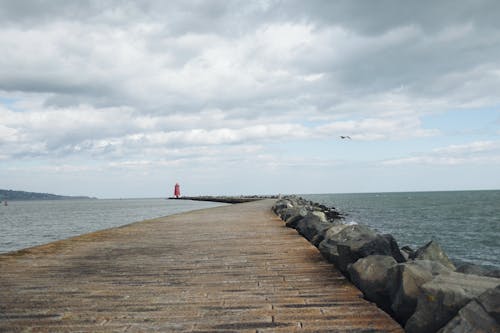 A pier with a lighthouse and a cloudy sky