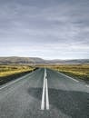 在多云的天空下，一条笔直的道路穿过冰岛风景如画的乡村