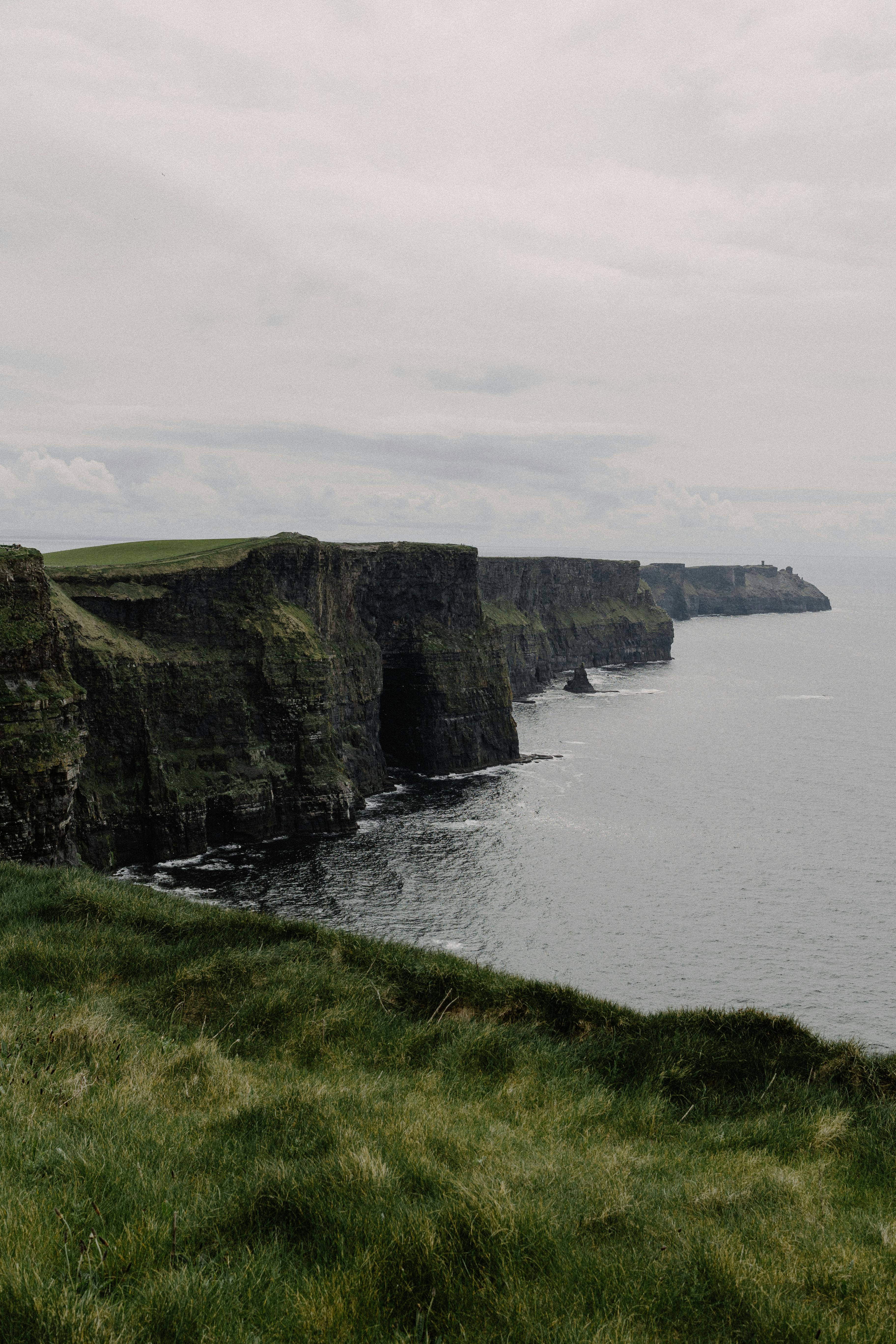 Breathtaking view of the Cliffs of Moher, overlooking the Atlantic Ocean on a cloudy day.
