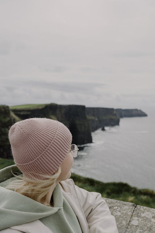 A woman wearing a pink beanie looking out over the ocean