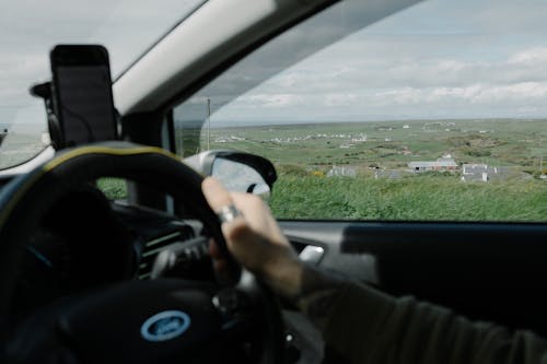 A person driving a car with a view of the countryside
