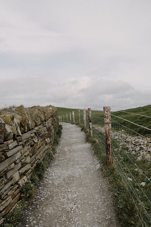 A path leading to a stone wall and fence