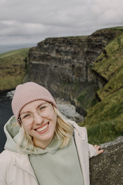 A woman smiling at the camera while standing on a cliff