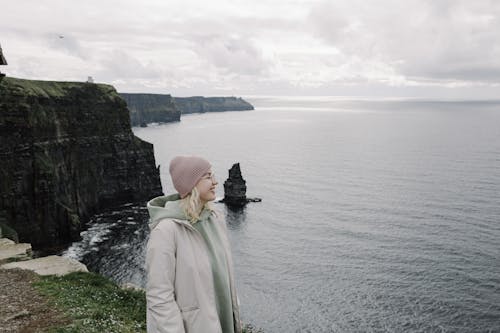 A woman standing on a cliff overlooking the ocean