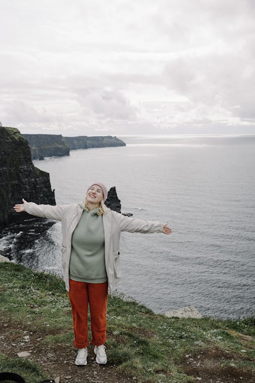 A woman standing on a cliff with her arms outstretched