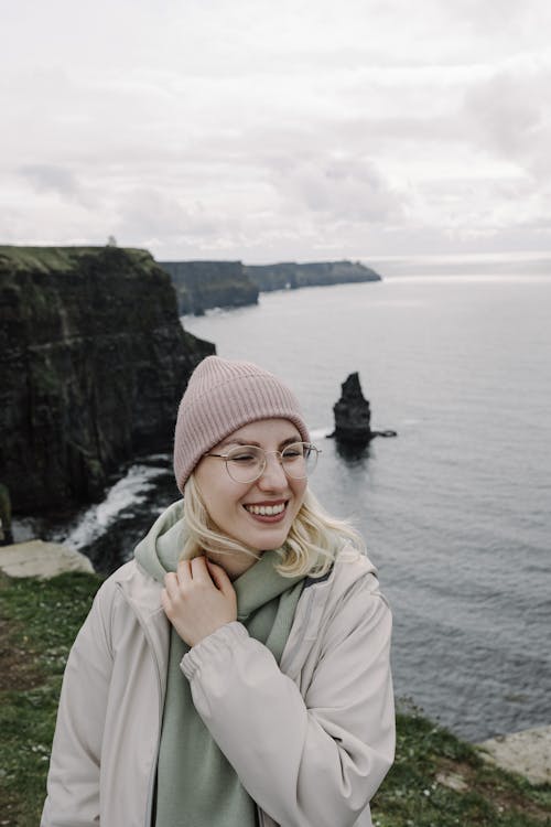 A woman in a pink hat smiling at the ocean