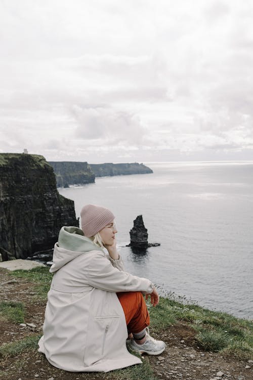 A woman sitting on a rock overlooking the ocean