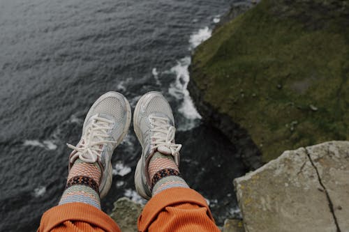 A person's feet are on the edge of a cliff