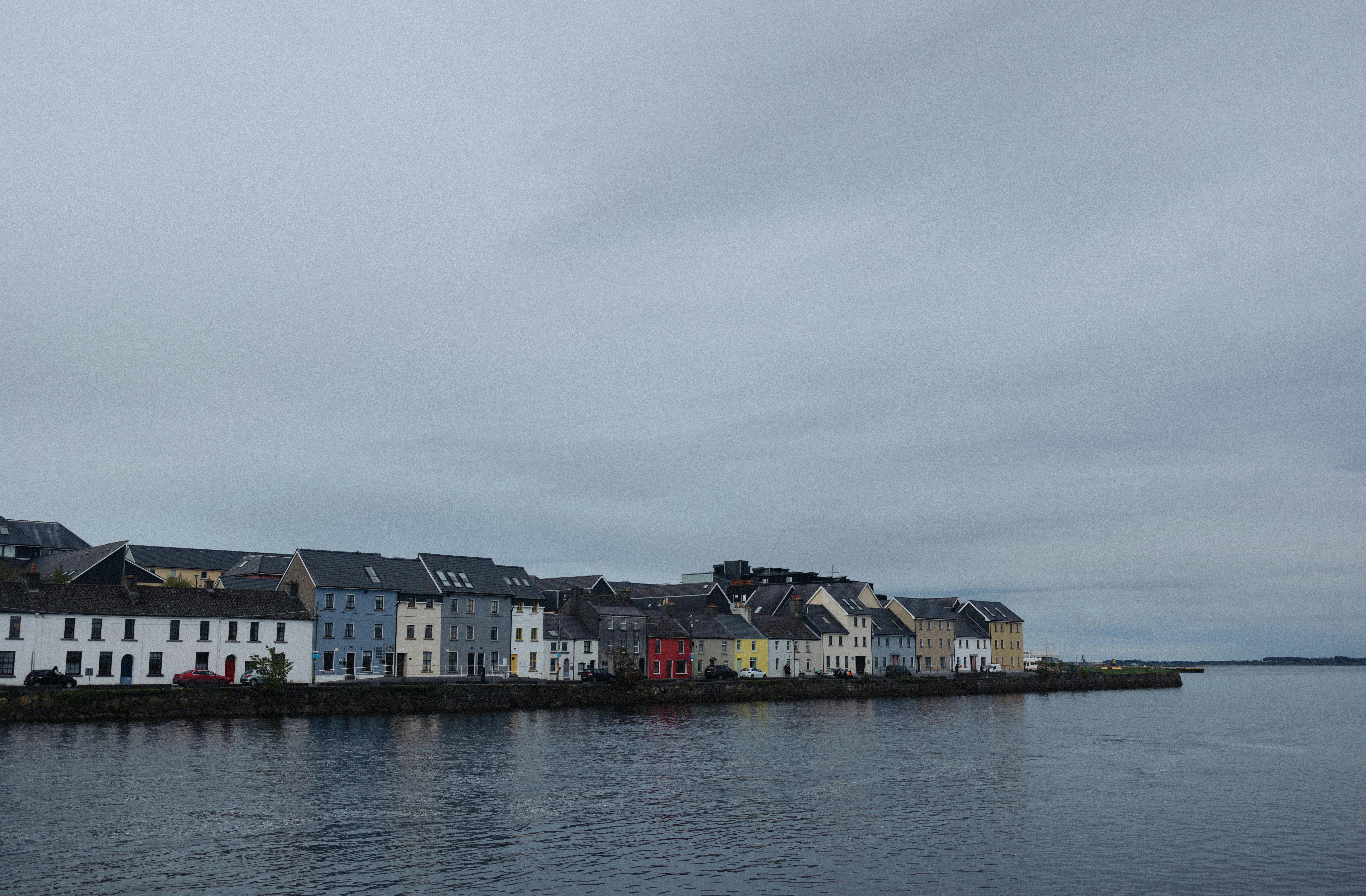 Quaint row of colorful houses along Galway's waterfront, evoking a serene Irish charm.
