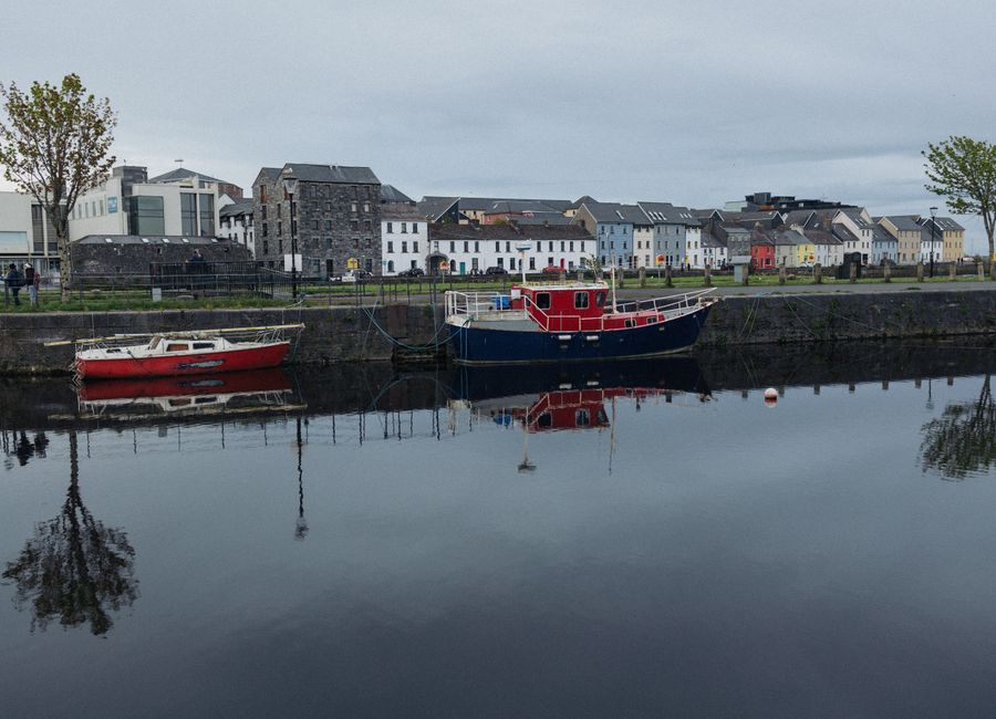 Charming view of colorful houses, moored boats, and calm river reflections in a vibrant urban town.
