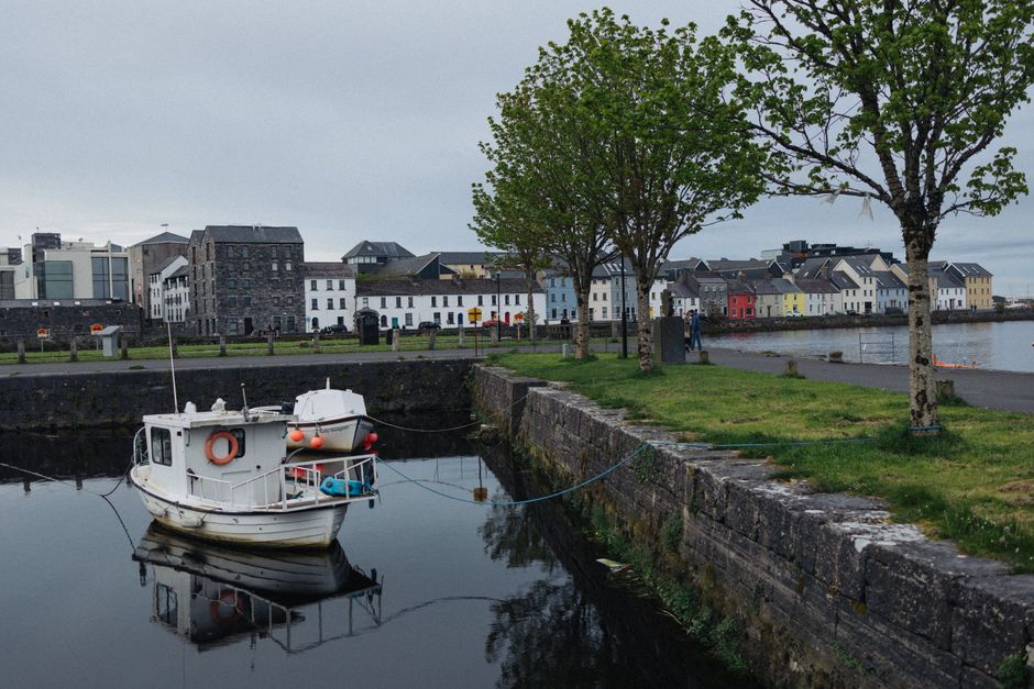 Calm waters with a moored boat reflecting Galway Calm waters with a moored boat reflecting Galway's colorful buildings along the dock.