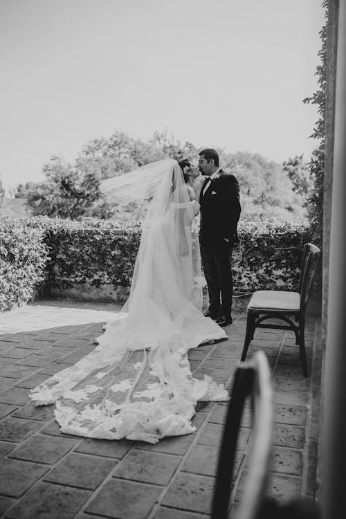 A bride and groom standing in front of a window