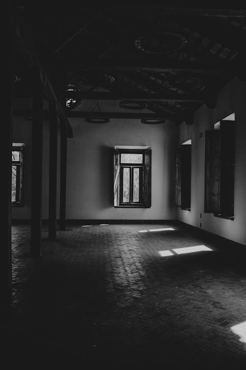 Black and white photo of an empty room with sunlight coming through the windows