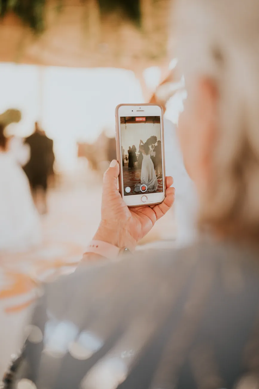 A wedding guest filming the celebration on their phone