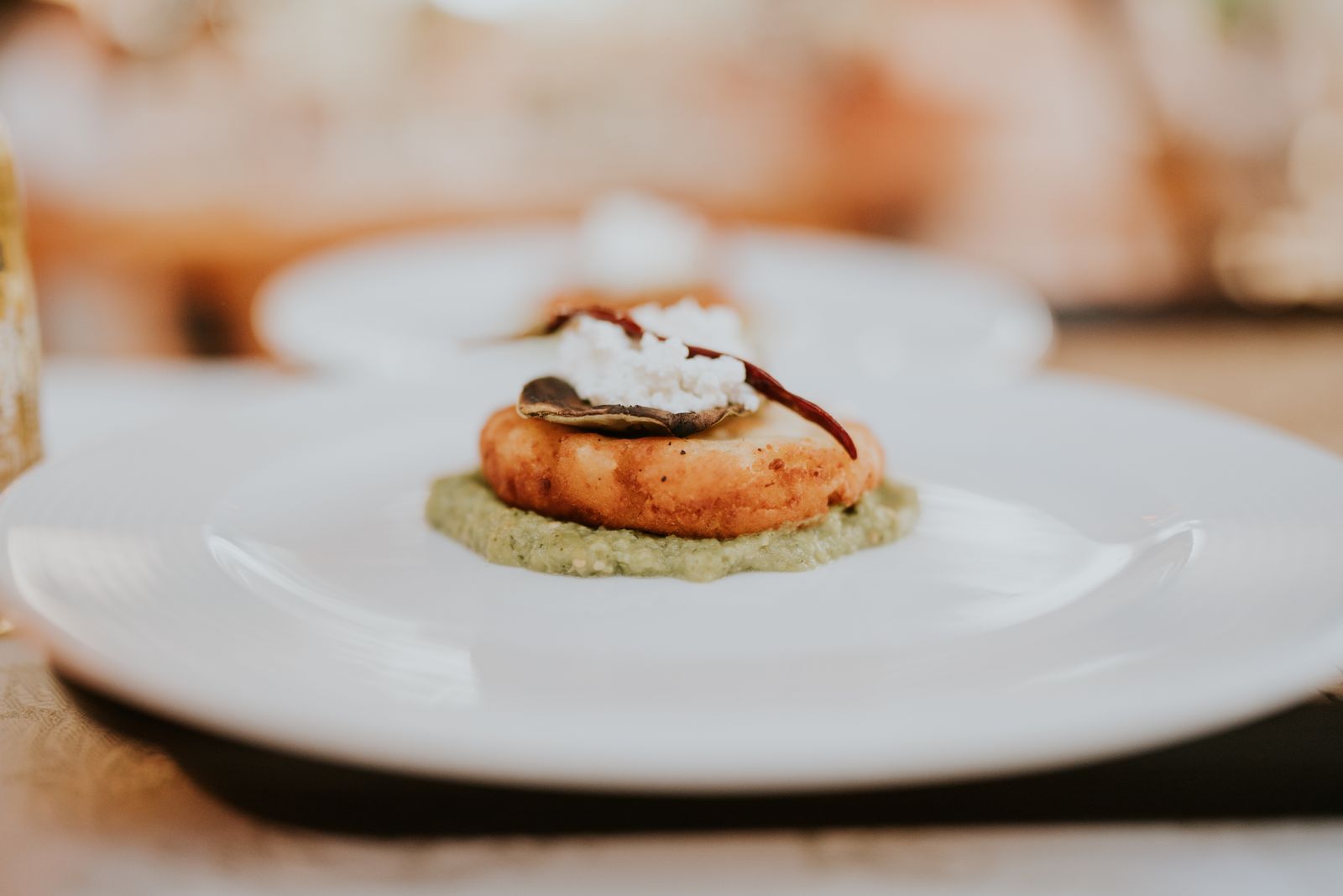A gourmet dish elegantly plated with a delicate appetizer on a white plate in an upscale restaurant setting.