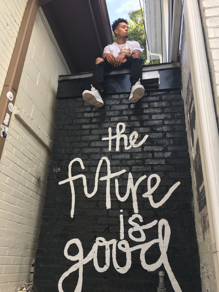 Man Sitting On Top Of Wall With The Future Is Good Print